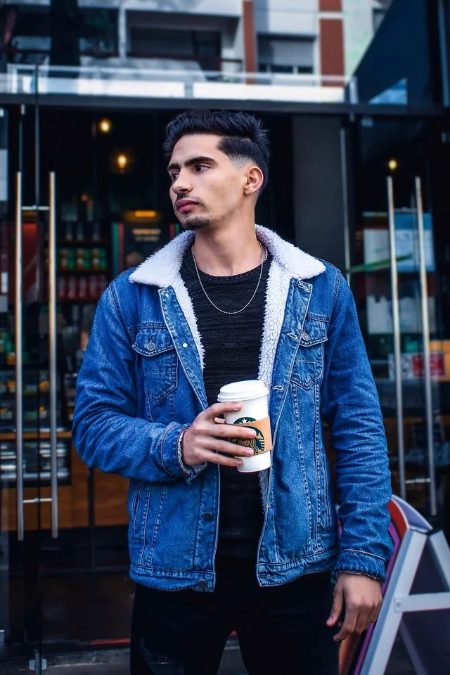 Man wearing a blue shearling denim jacket and holding a coffee cup